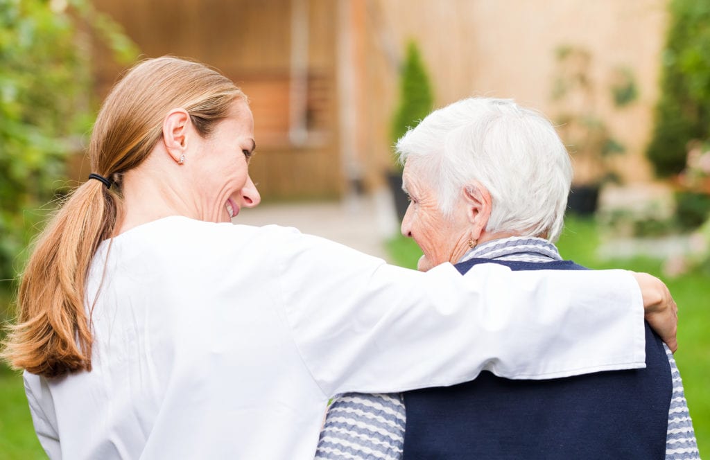 Young carer walking with the elderly woman in the park